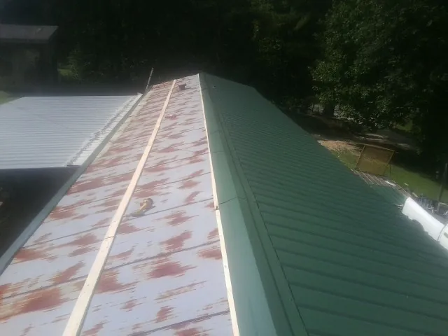 Old rusted panels beside newly installed green metal roofing — Wind Damage Roof Repair by Roofing Brothers in Shenandoah